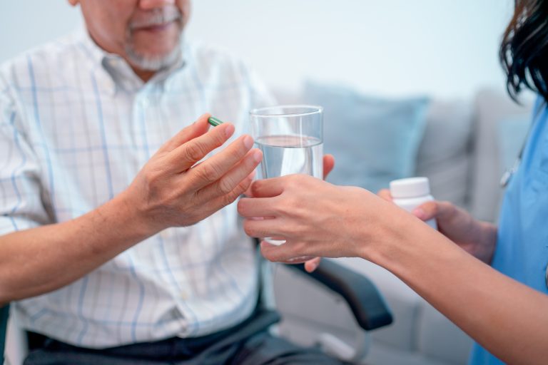 Asian senior man hold medicine pill and discuss with nurse or doctor during homecare service.